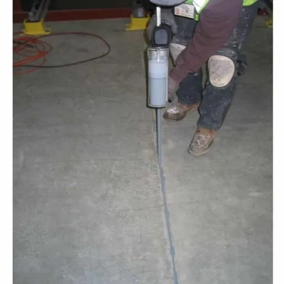 Worker sealing crack in concrete floor