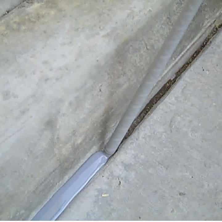 Camouflaged snake blending into concrete sidewalk edge