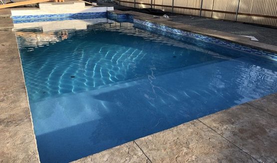 Clear blue backyard swimming pool with shallow ledge