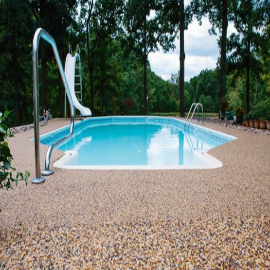 Backyard swimming pool with slide and pebble deck