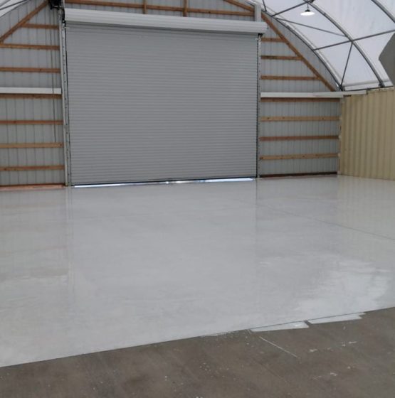 Glossy epoxy floor inside metal garage with roll-up door