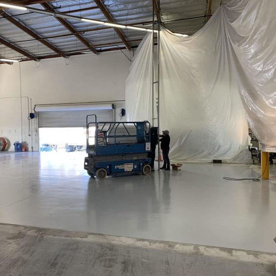 Worker on scissor lift inside large warehouse